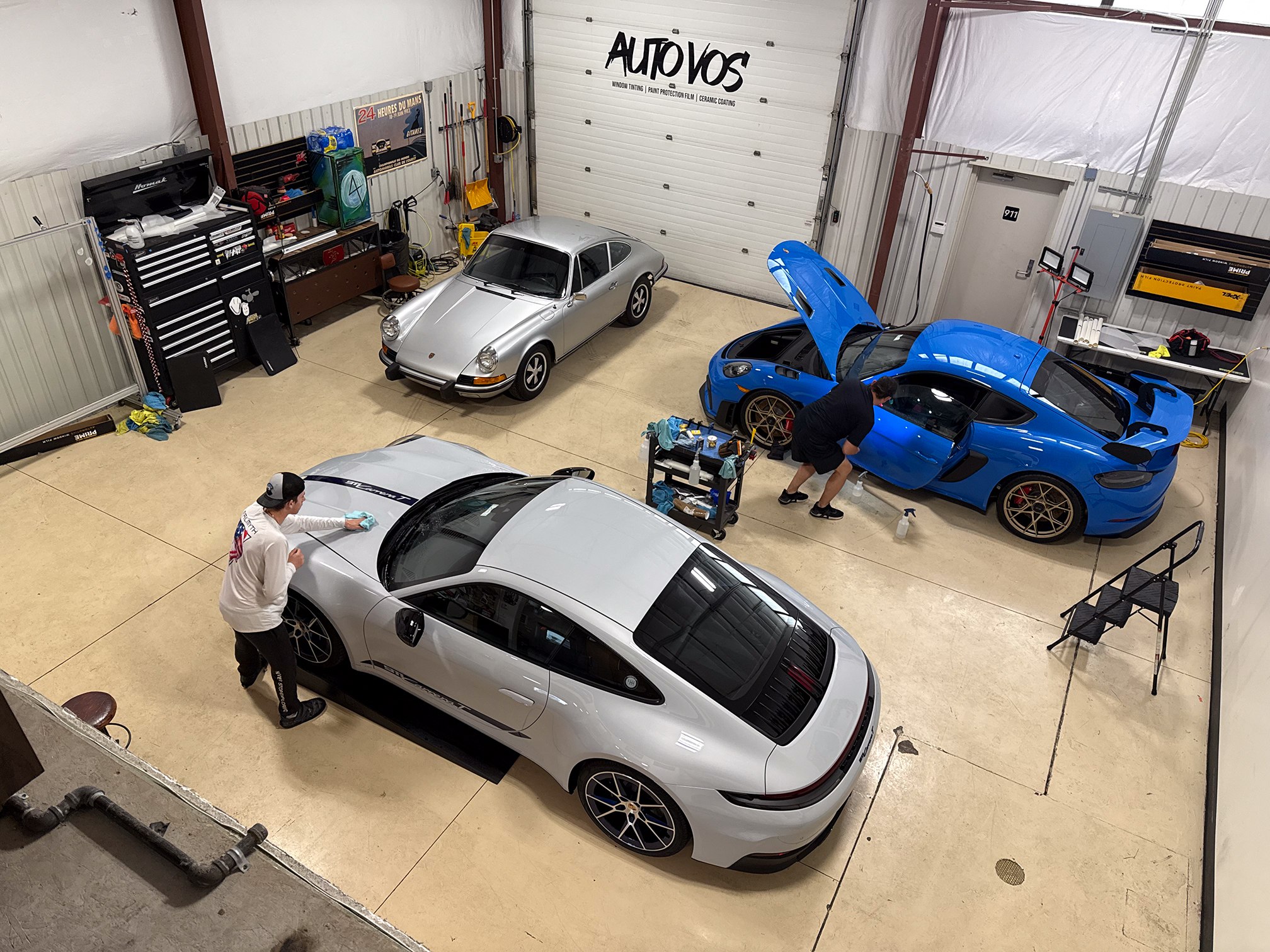 Overhead view of technicians working beside white and blue Porsches Overhead view of technicians working beside white and blue Porsches