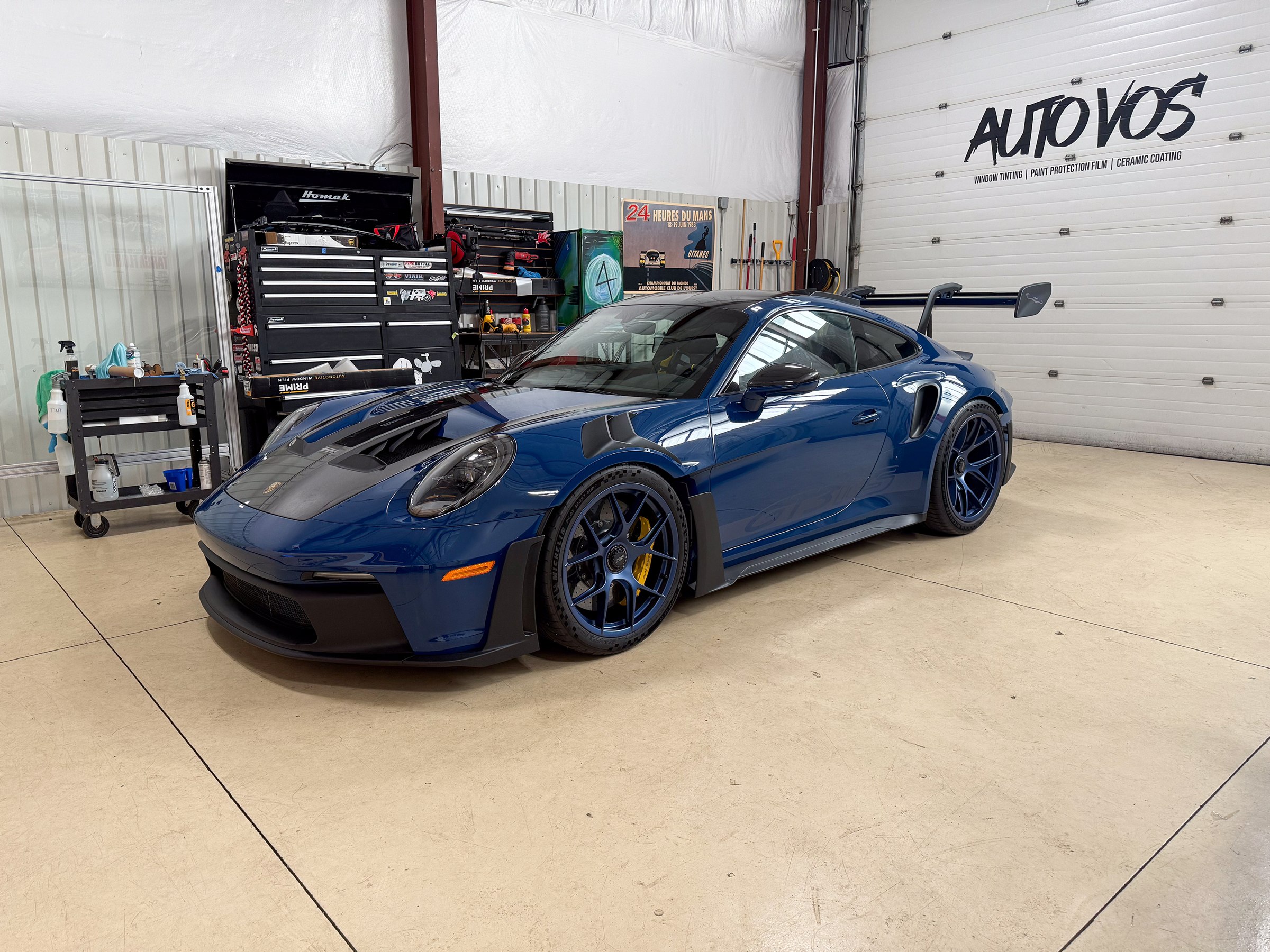Dark blue Porsche 911 with a dark hood and rear wing in the workshop Dark blue Porsche 911 with a dark hood and rear wing in the workshop