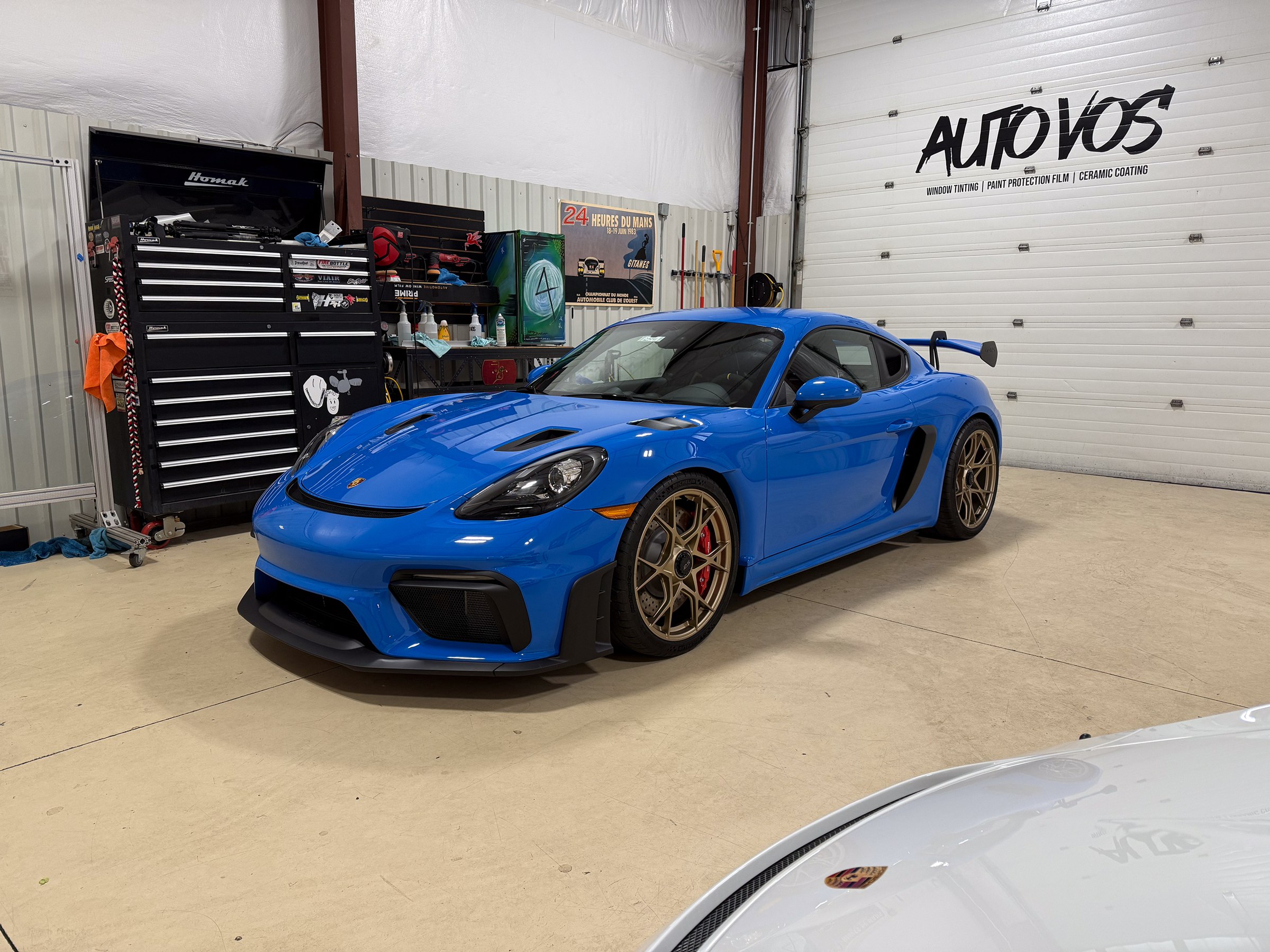 Blue Porsche Cayman with bronze wheels in the Auto Vos workshop