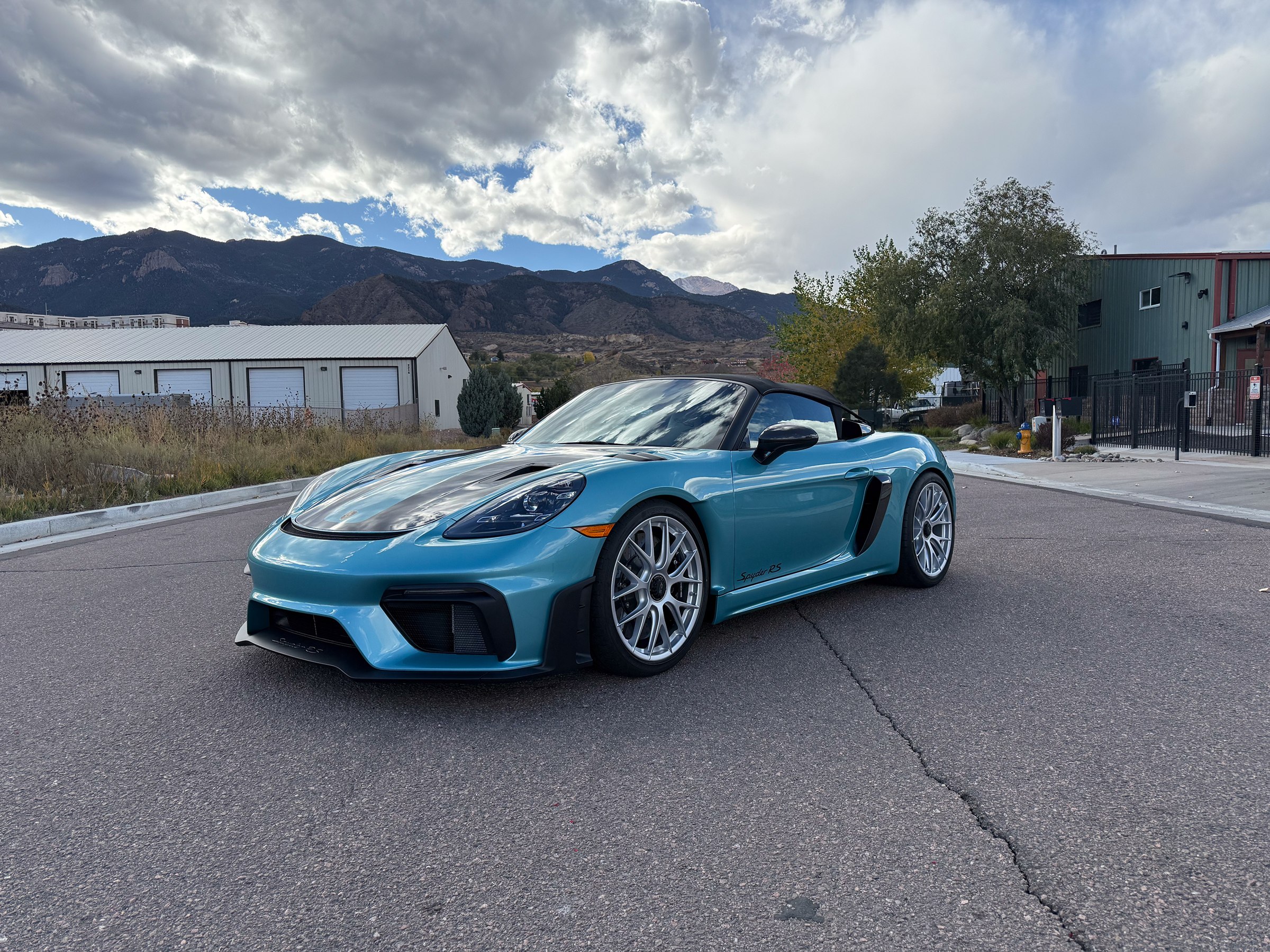 Light blue Porsche convertible outside the workshop with mountains behind it Light blue Porsche convertible outside the workshop with mountains behind it