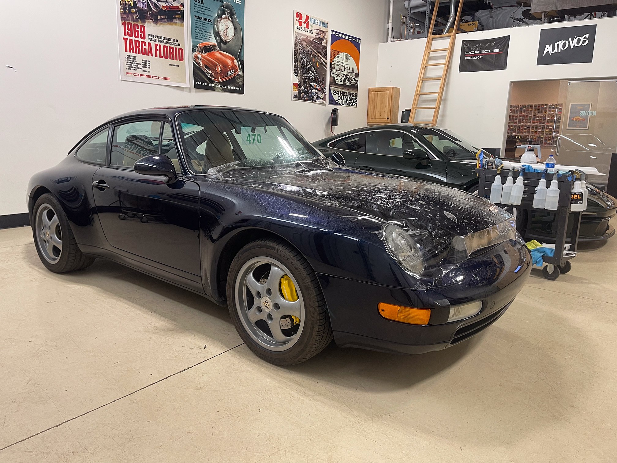 Dark blue classic Porsche 911 with wet clear film across its hood Dark blue classic Porsche 911 with wet clear film across its hood