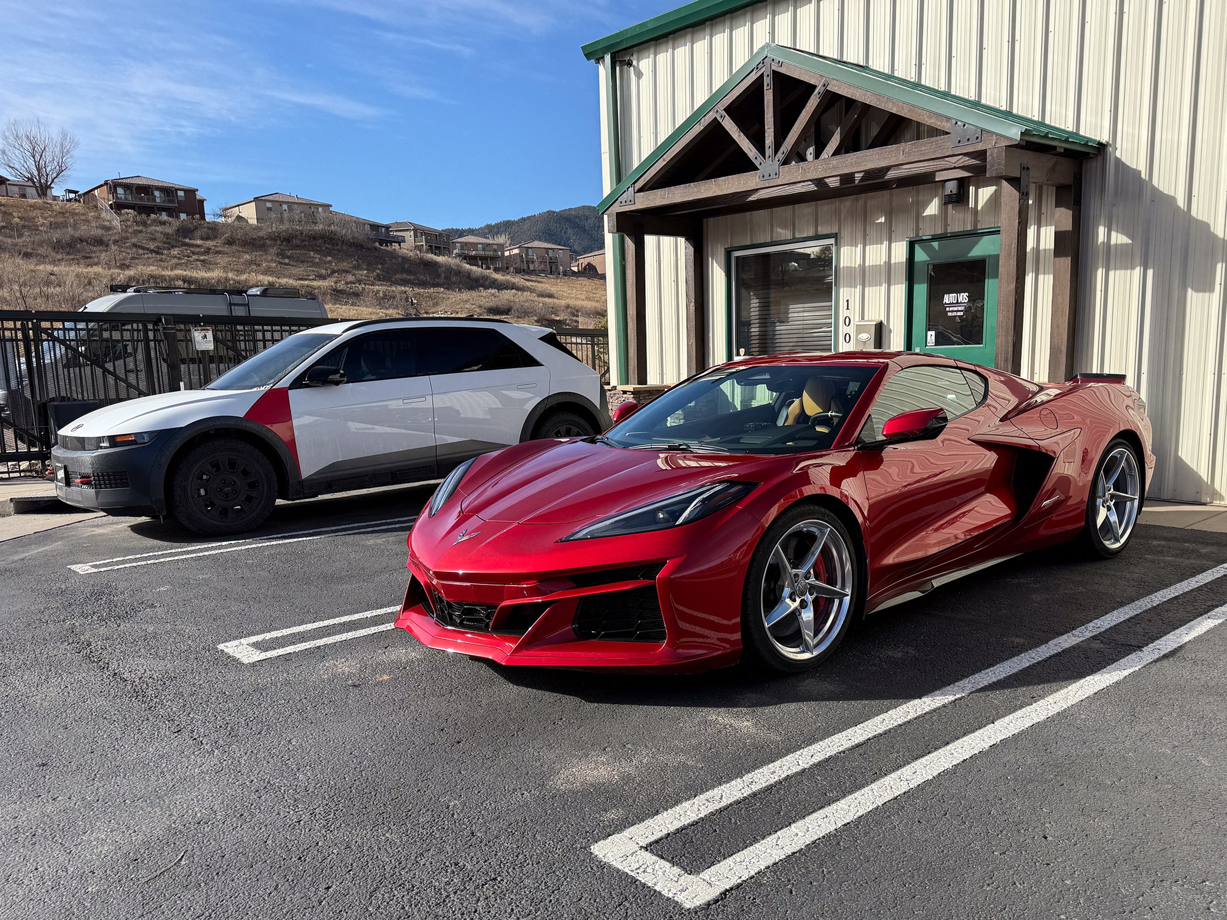 Red Chevrolet Corvette parked outside the Auto Vos entrance Red Chevrolet Corvette parked outside the Auto Vos entrance