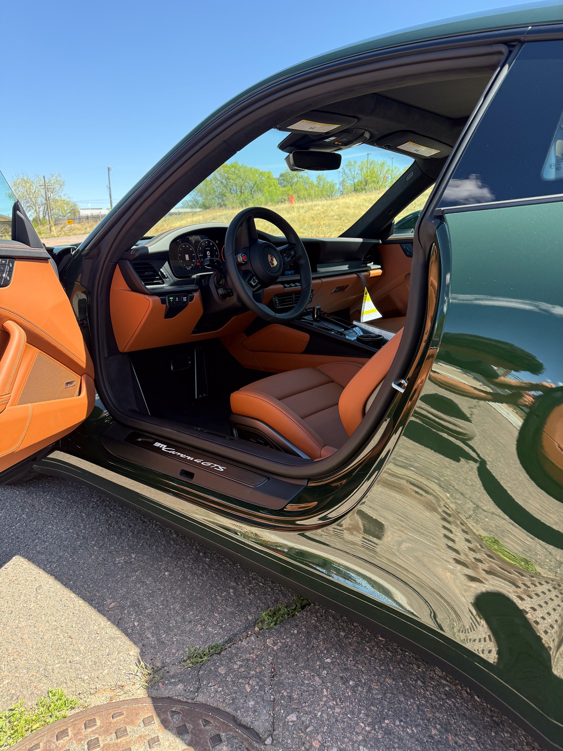 An open door frames the cabin and side glass of a green coupe An open door frames the cabin and side glass of a green coupe.