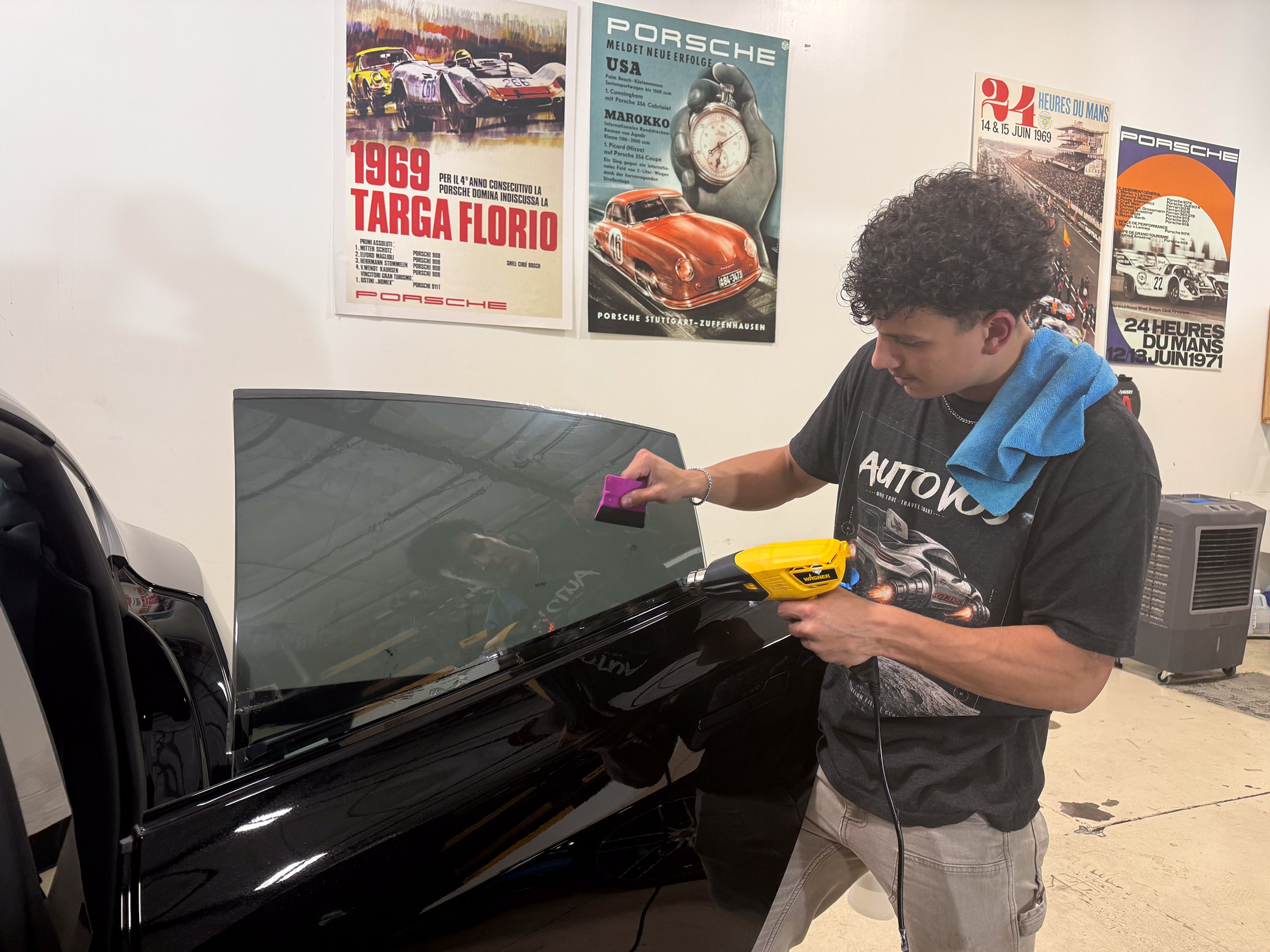 A technician shapes window film on a glass panel in the Auto Vos studio. A technician shapes window film on a glass panel in the Auto Vos studio.