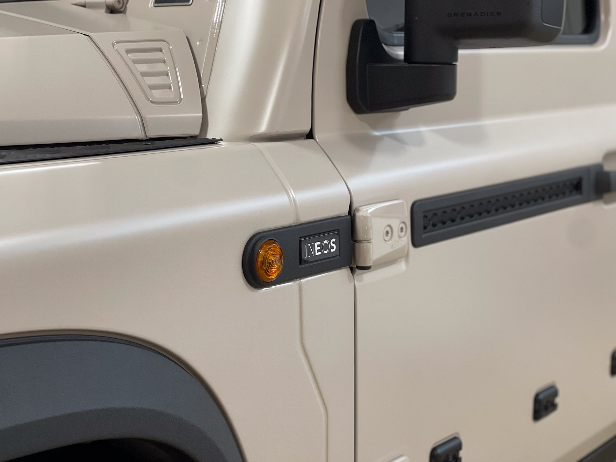Beige INEOS Grenadier door hinge, side marker and mirror in close-up Beige INEOS Grenadier door hinge, side marker and mirror in close-up