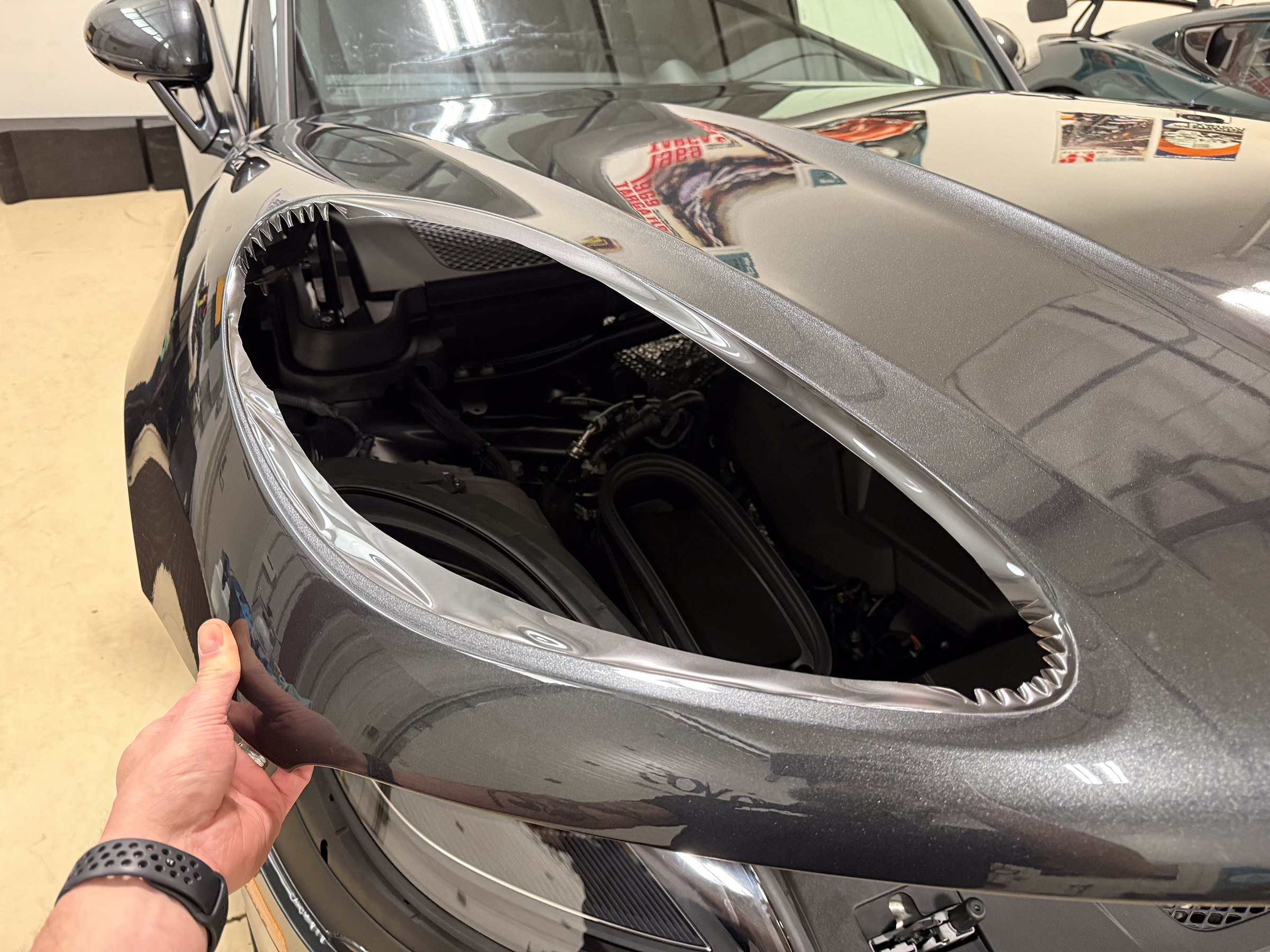 Hand holding a gray Porsche panel with film folded around the empty headlamp opening Hand holding a gray Porsche panel with film folded around the empty headlamp opening