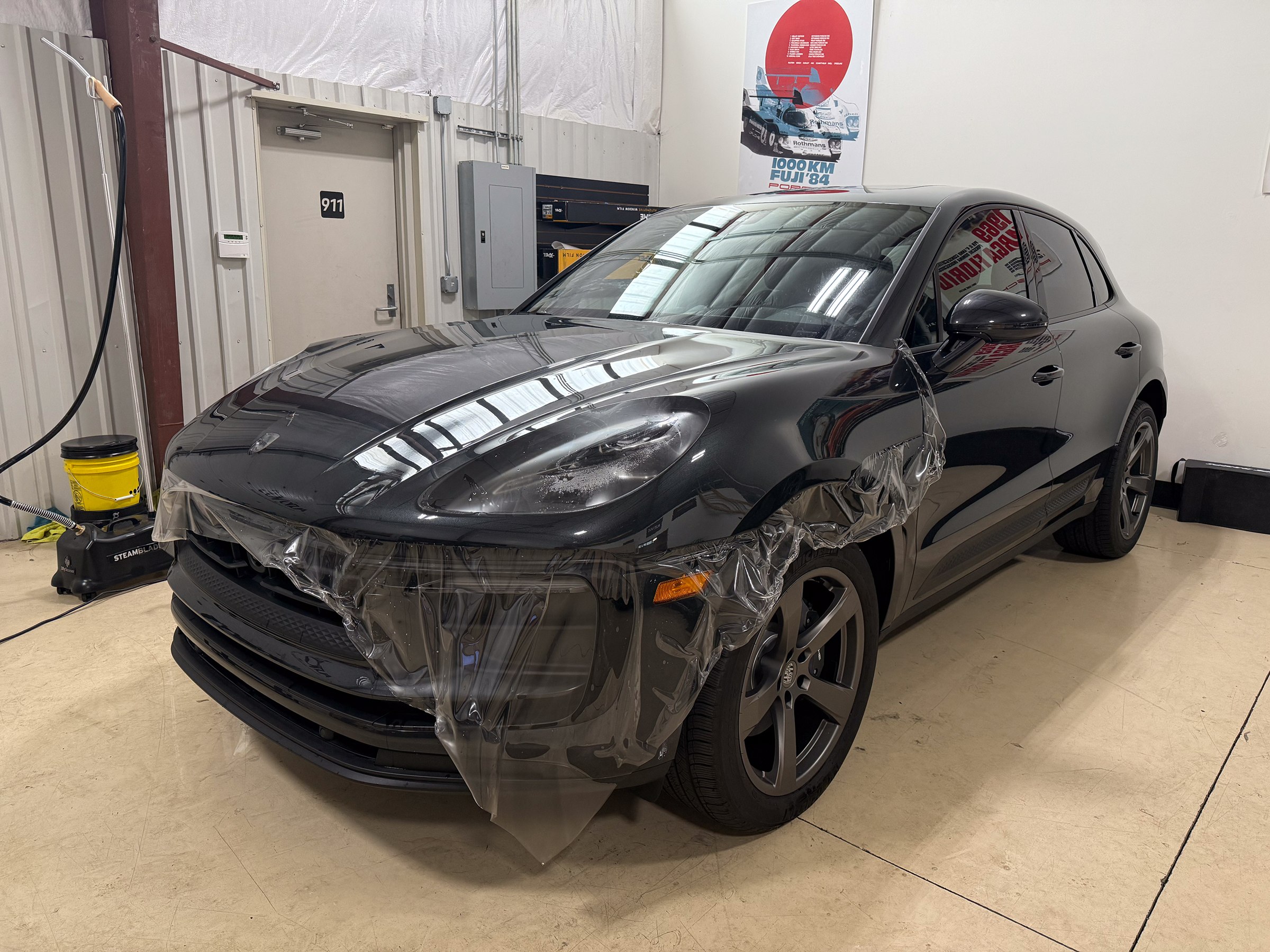 Dark Porsche Macan with wet film hanging across its front bumper Dark Porsche Macan with wet film hanging across its front bumper