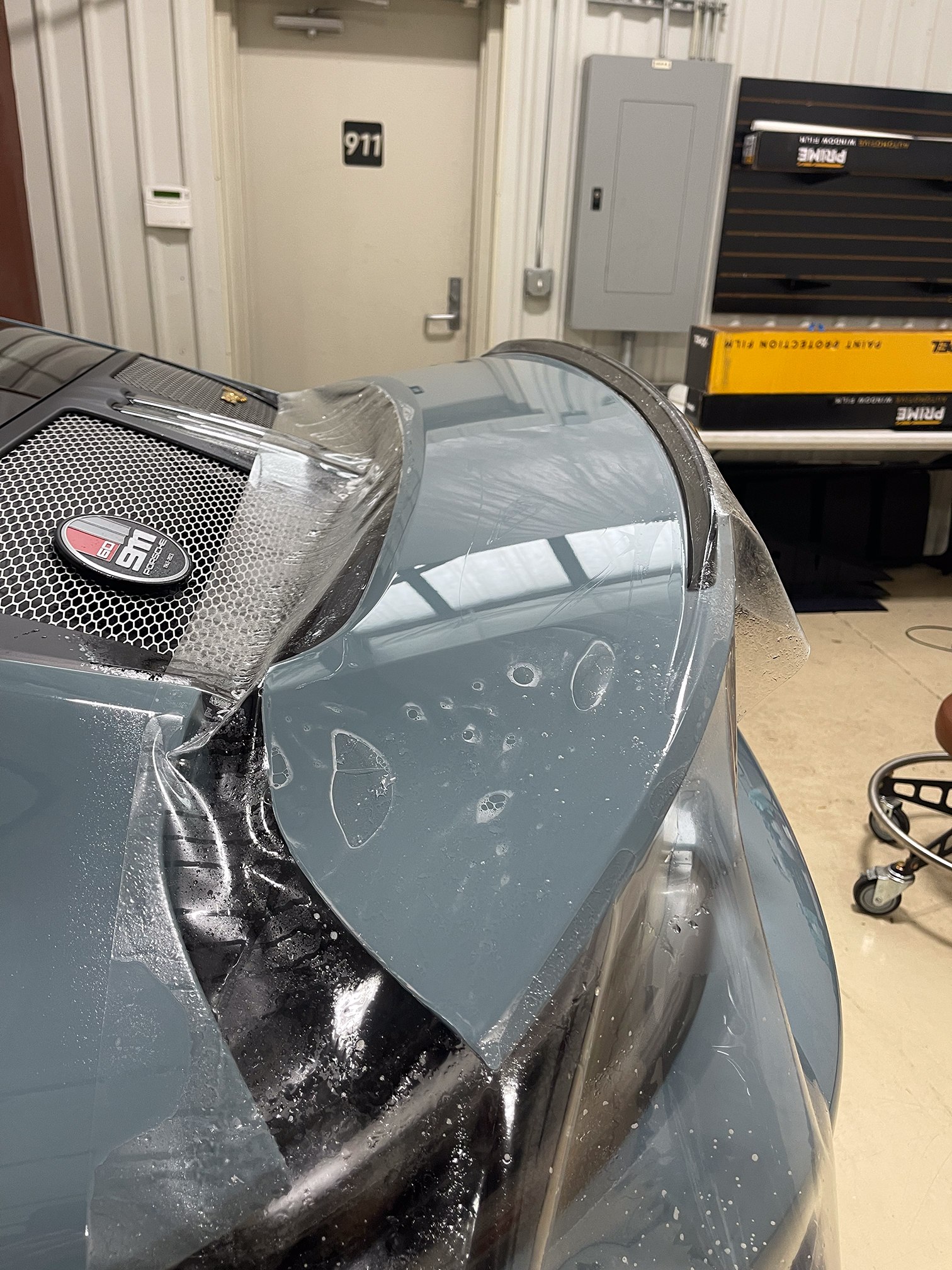 Wet clear film draped over a blue-gray Porsche rear spoiler Wet clear film draped over a blue-gray Porsche rear spoiler