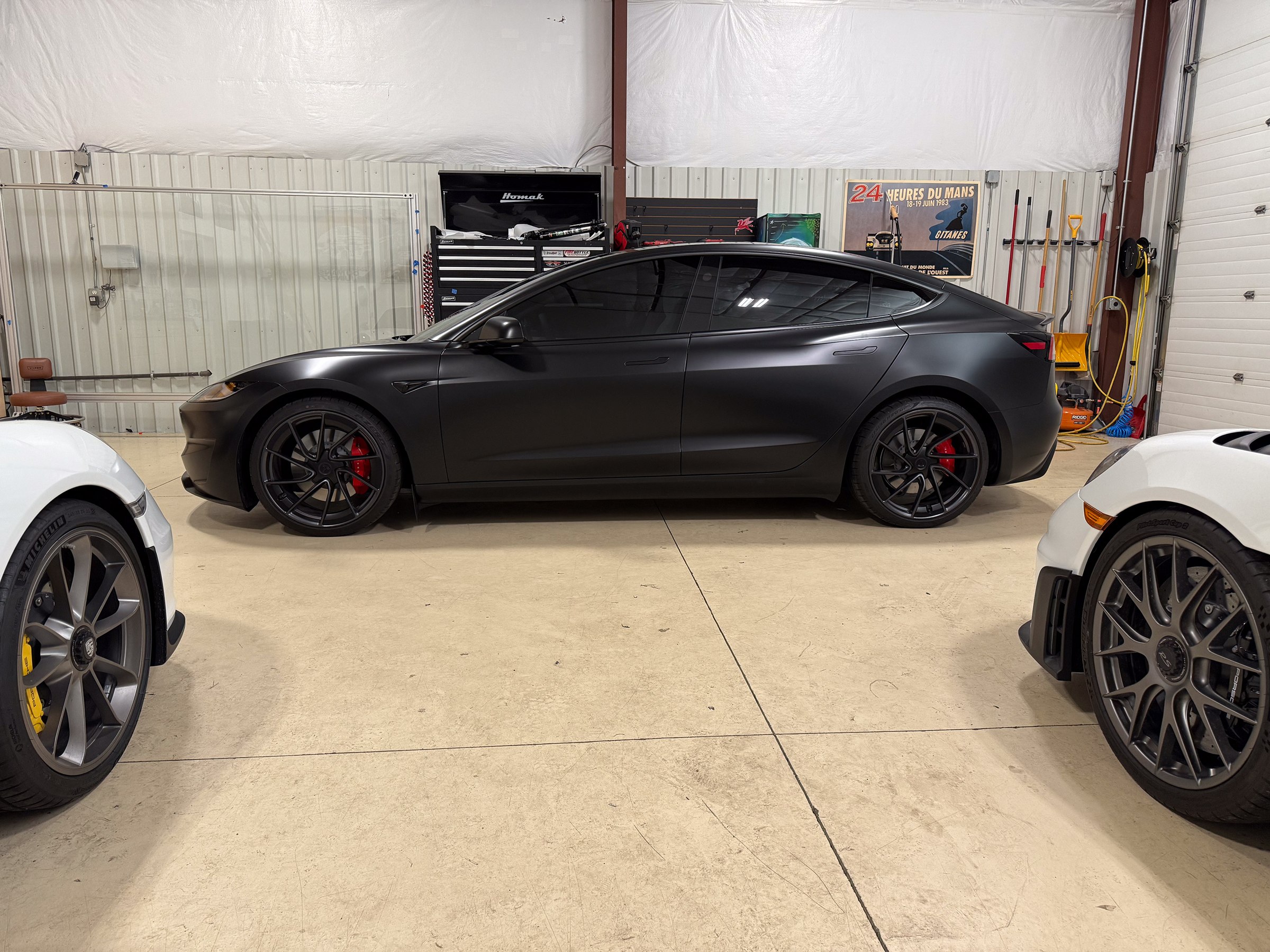 Dark matte Tesla in side profile inside the workshop Dark matte Tesla in side profile inside the workshop