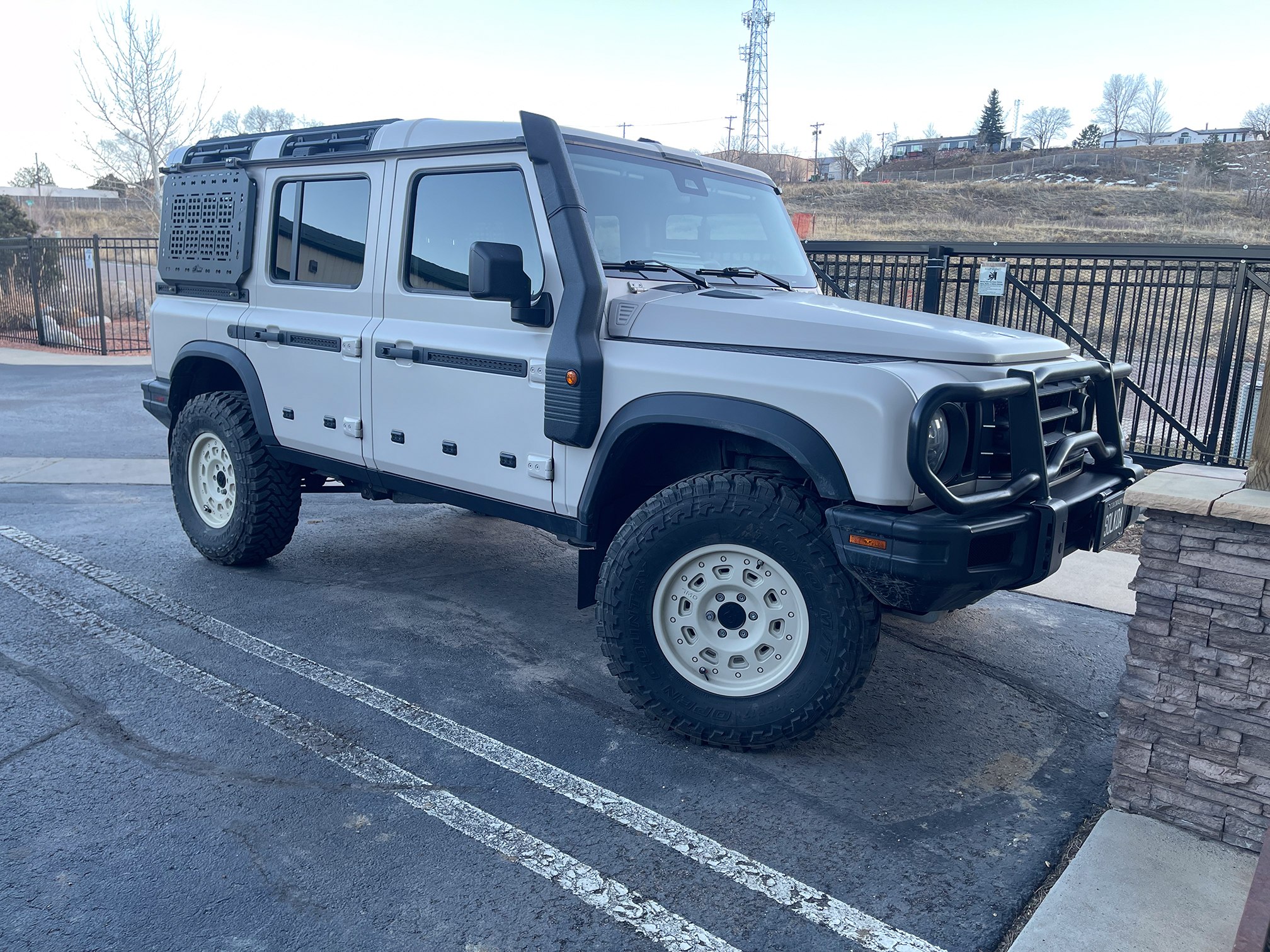 White INEOS Grenadier with roof rack and black trim outside the workshop White INEOS Grenadier with roof rack and black trim outside the workshop