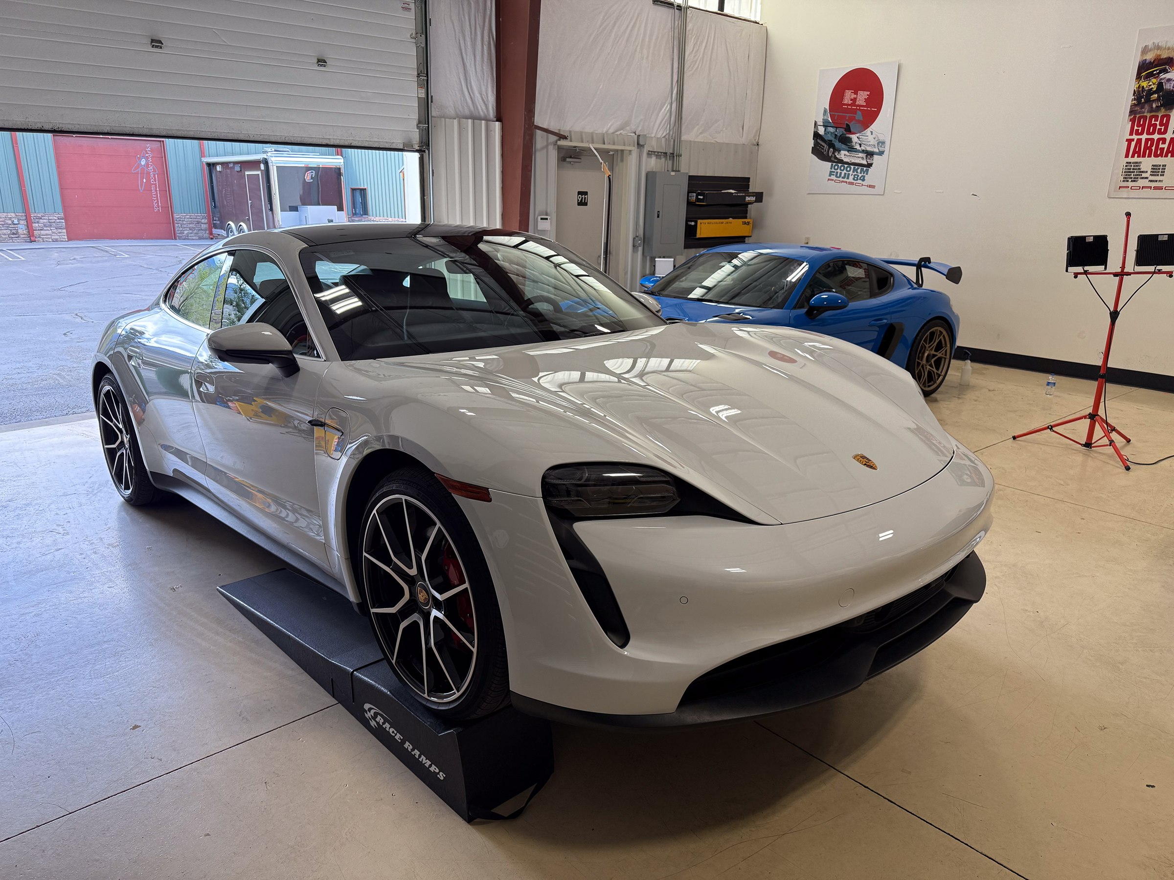 White Porsche Taycan photographed from the front quarter inside the workshop White Porsche Taycan photographed from the front quarter inside the workshop